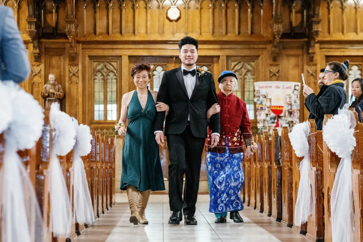 Groom walking down the aisle with mother and grandma