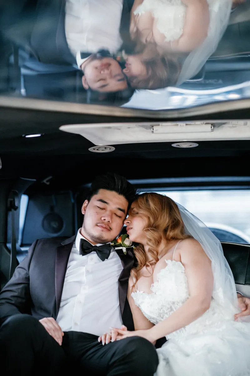 Bride and groom groom hugging in limo after wedding ceremony