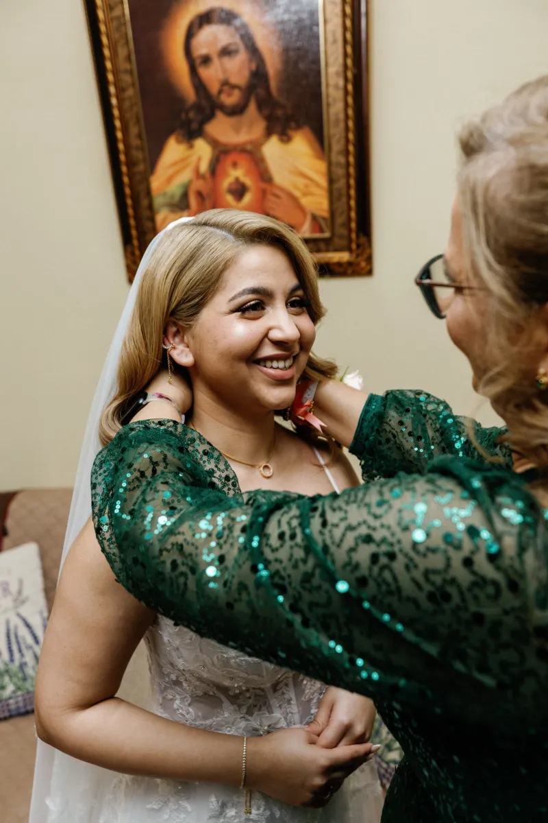 Mom putting neckless on bride