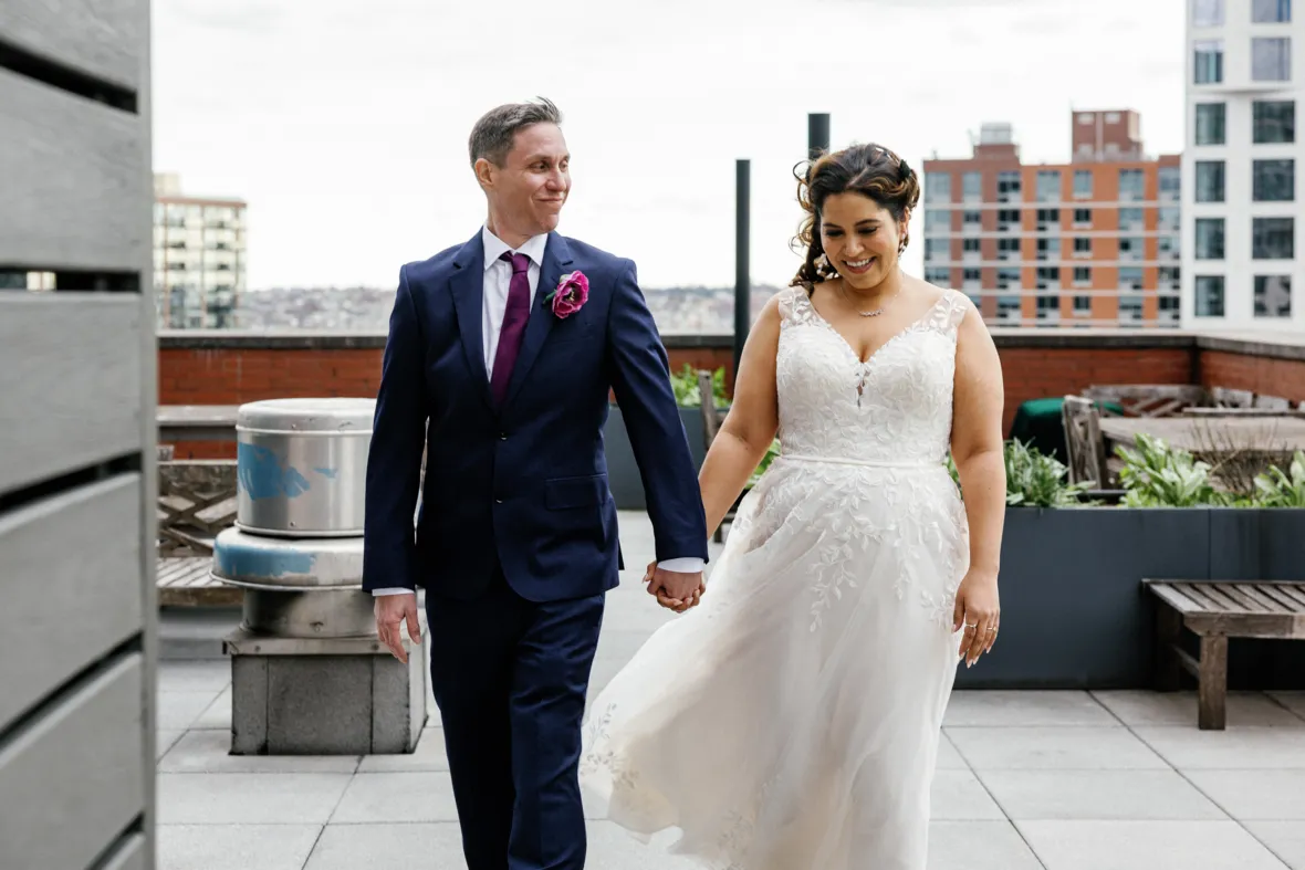 Bride and groom walking on rooftop and holding hands