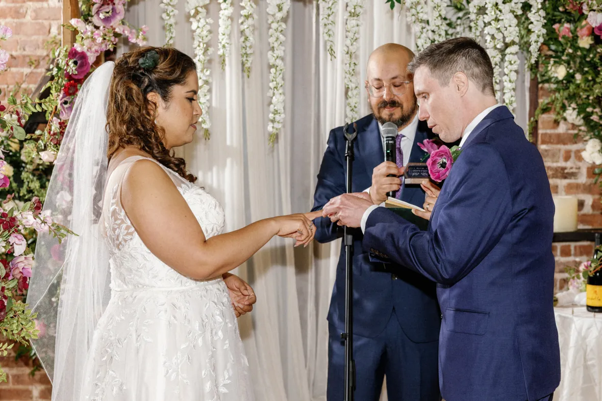 Groom putting ring on brides finger