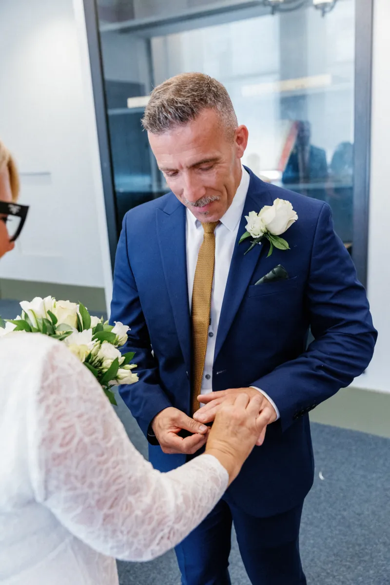 Bride putting ring on grooms finger