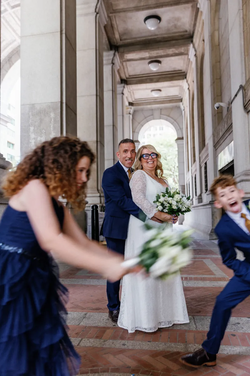 Couple posing for photos while kids are running in front of camera