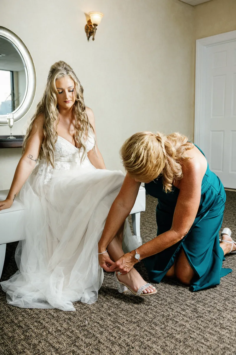 Maid of honor helping bride put the shoes on