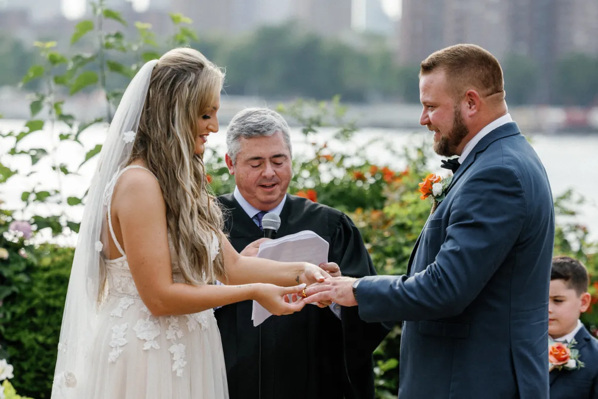 Bride putting wedding ring on grooms finger