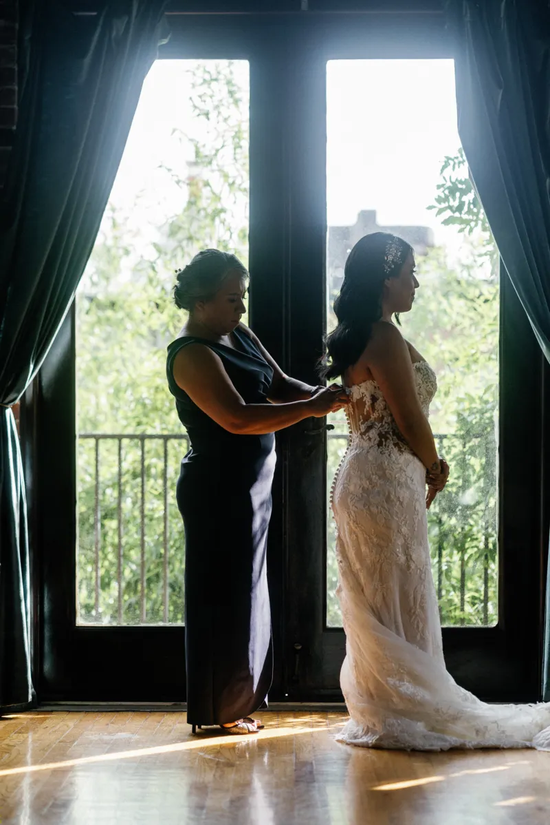 Mother helping bride put the dress on