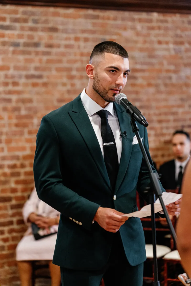 Groom reading personal wedding vows during ceremony