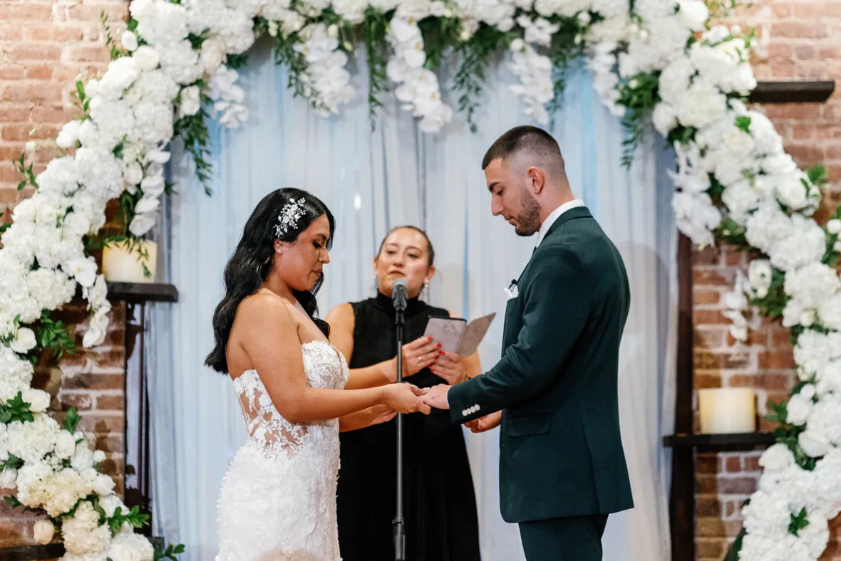 Bride putting ring on grooms finger during wedding ceremony