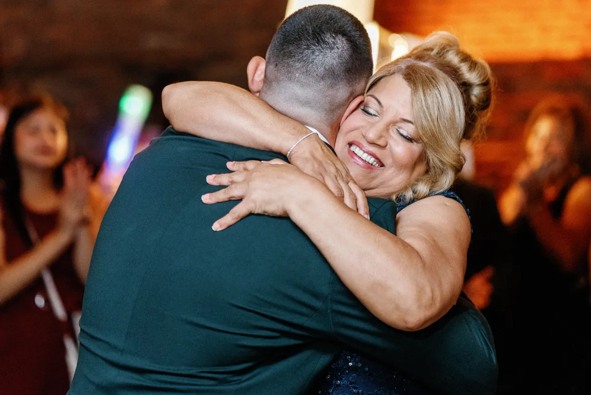 Mother hugging groom during mother son dance