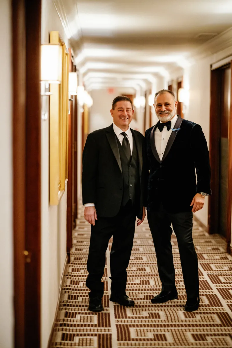 Groom and best man portrait in hotel hallway