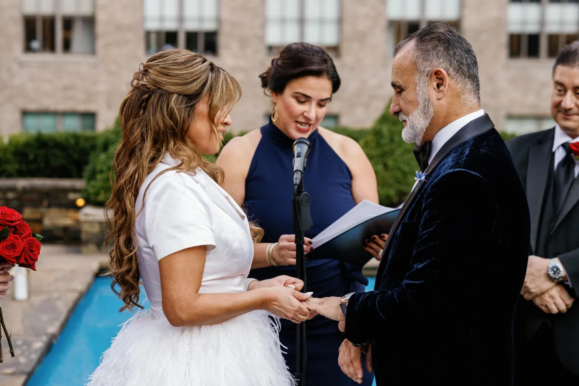 Bride putting a ring on grooms finger during wedding ceremony