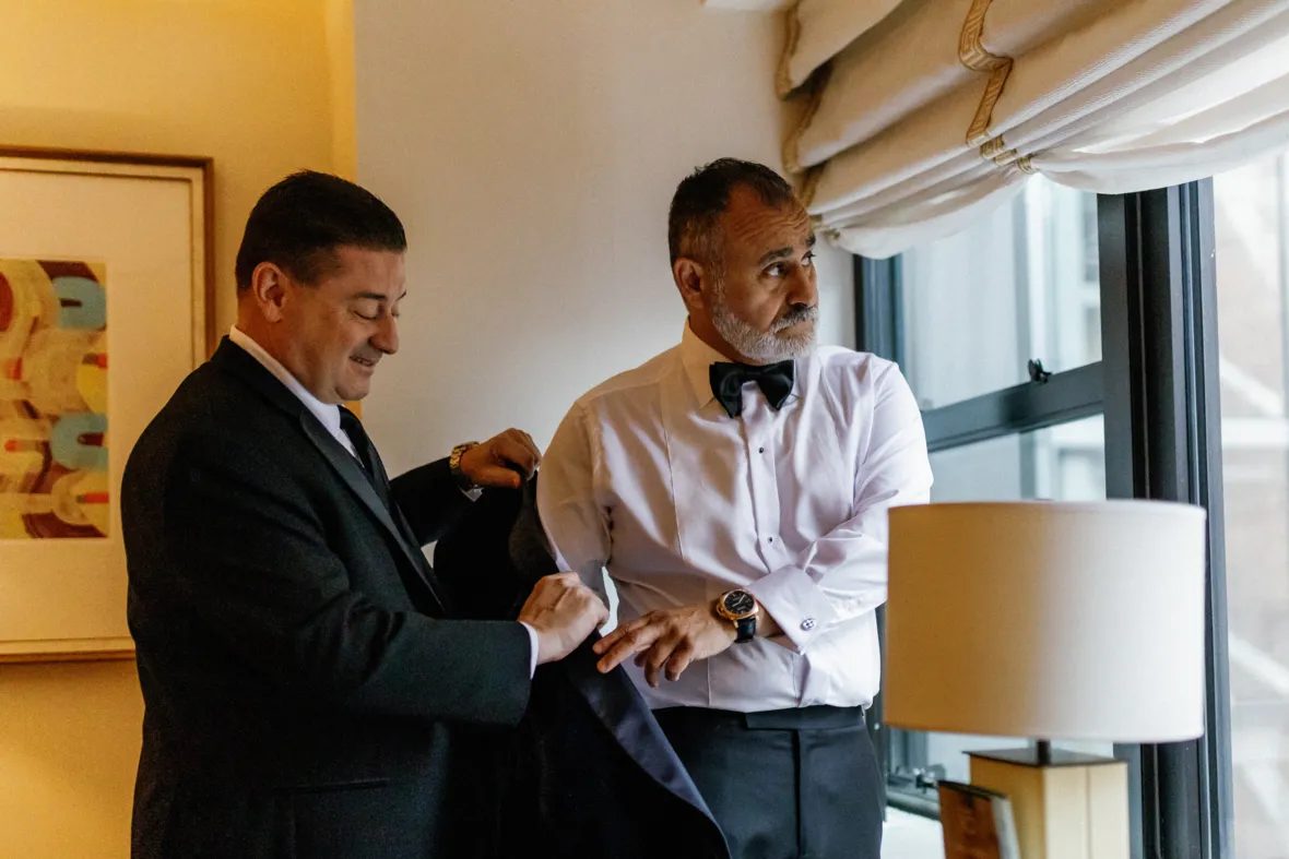 Best man helping groom put the suit on