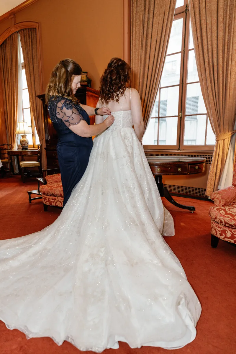 Mother helping bride put the wedding dress on