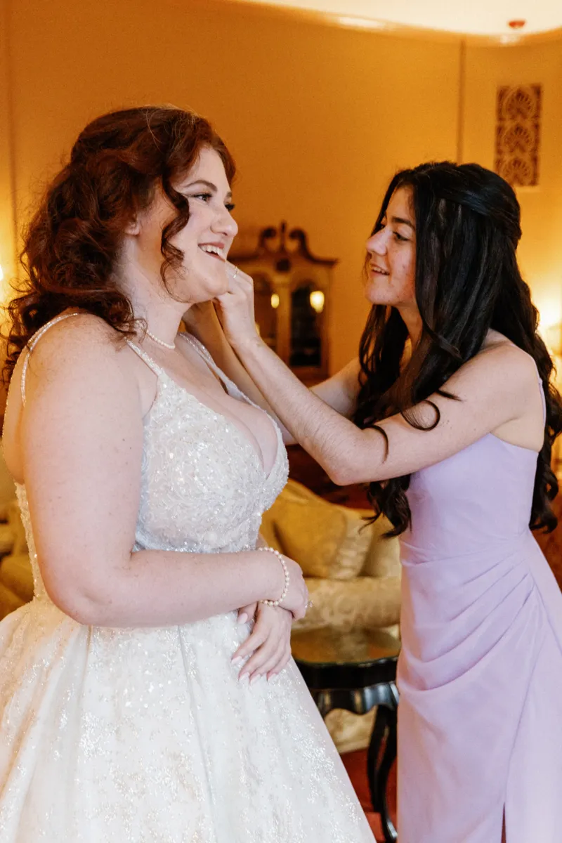 Sister helping bride put the earrings on