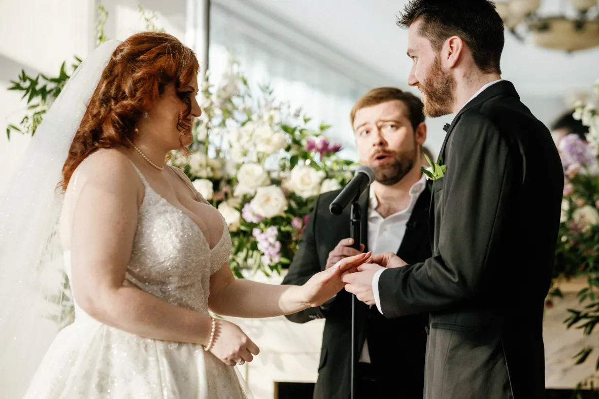 Groom putting wedding ring on brides finger