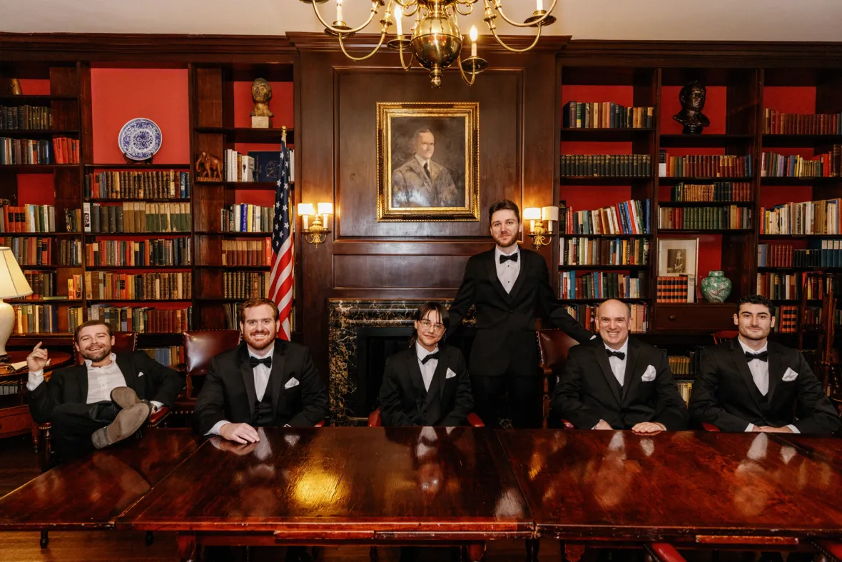 Groom with groomsmen sitting on large wooden table